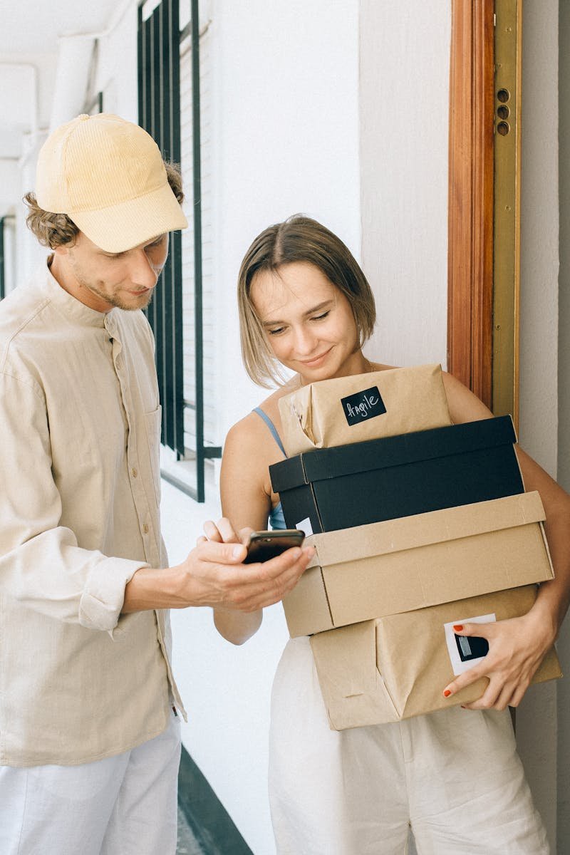 A man and woman engaged in a home delivery package exchange, smiling.